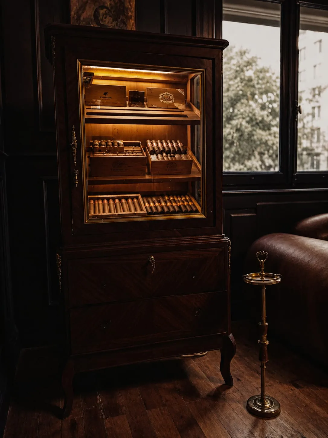 Illuminated antique humidor cabinet holding boxes of Cuban cigars