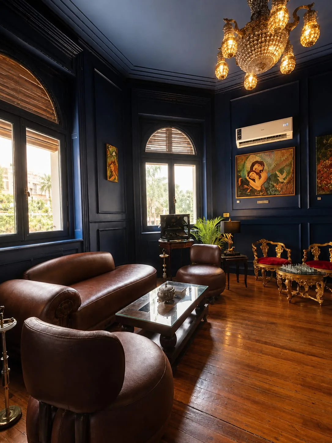 The blue salon with leather club chairs, gilded seating and a crystal chandelier