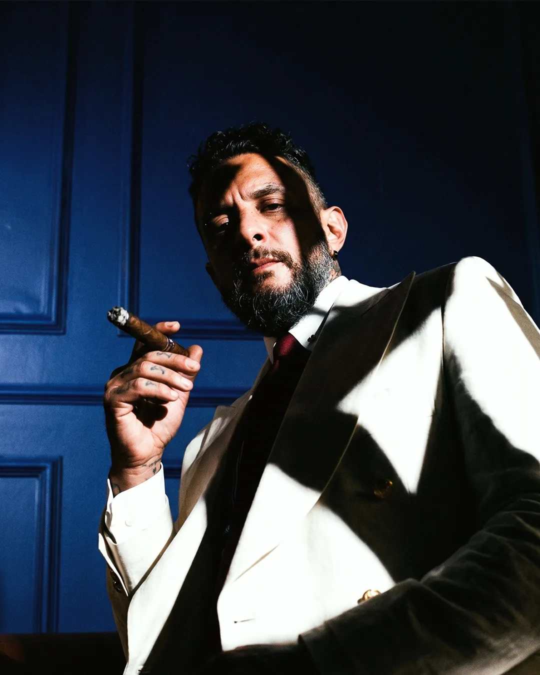 Member in a cream double-breasted suit with a lit cigar in the panelled salon